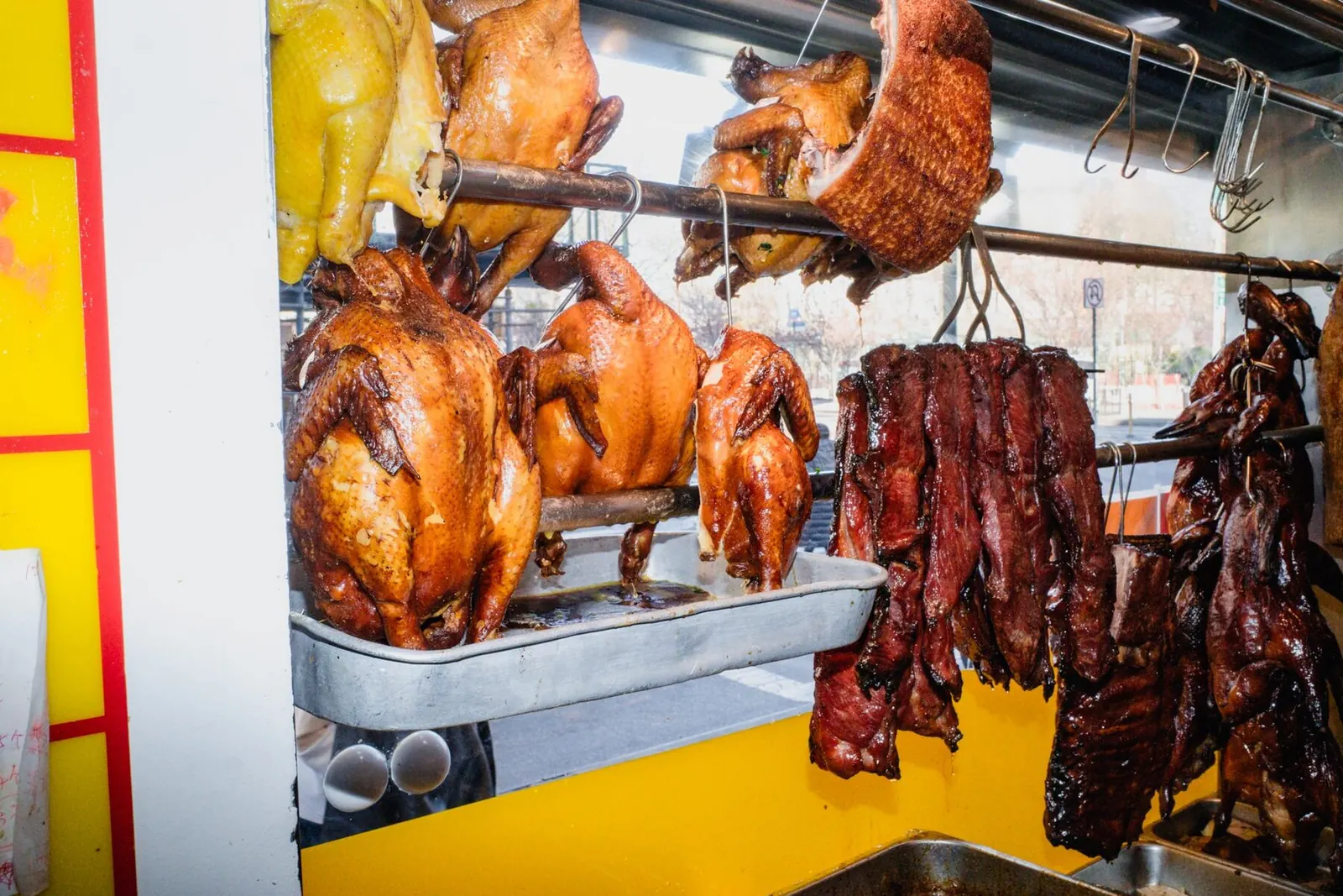 Soy sauce chickens and char siu hanging in the front window